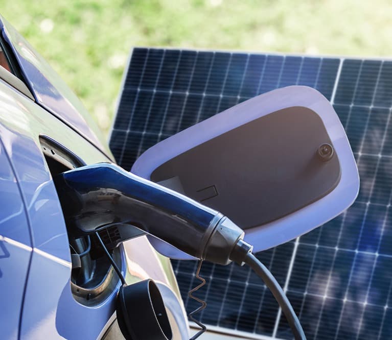 Elektroauto wird geladen, im Hintergrund ein Photovoltaikmodul